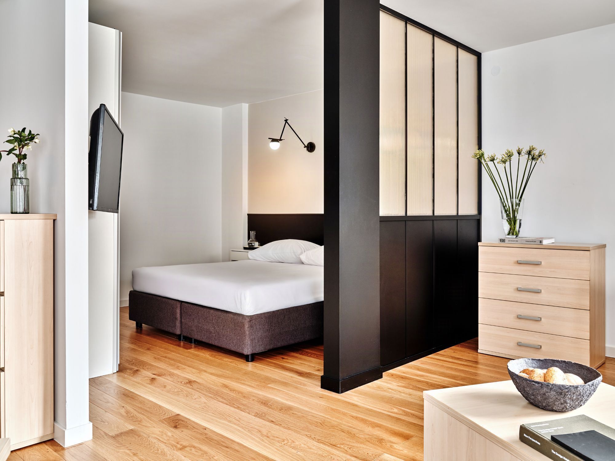 Ein modernes Schlafzimmer mit Bett, Nachttisch, Lampe und Kommode.