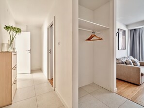 A modern apartment with a hallway leading to a living area, a wooden wardrobe, and a hanging clothes rack. - Media Park (Warsaw)
