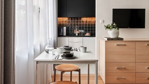 Eine moderne Küche mit Esstisch für zwei Personen, einer Kaffeemaschine und einem an der Wand befestigten Fernseher.
