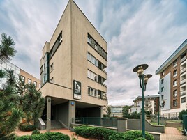A modern building with a unique triangular shape, multiple balconies, and a sign indicating it is a medical park apartment building.