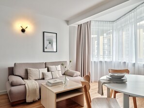 A modern living room with a sofa, a coffee table, and a dining table. - Media Park (Warsaw)
