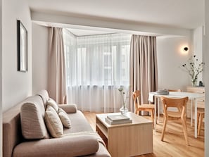 A modern living room with a sofa, a coffee table, and a dining area with chairs and a table. - Media Park (Warsaw)