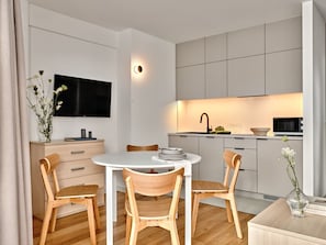 Une cuisine moderne équipée d’un téléviseur à écran plat, de chaises en bois et d’une table à manger.
