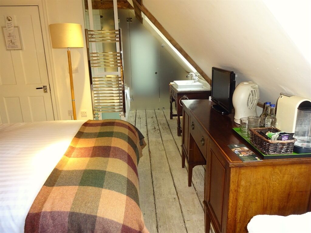 A bedroom with a bed, a desk, a television, and a radiator.