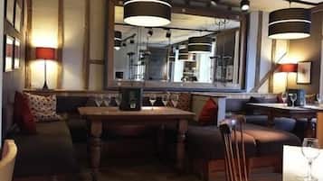 Un restaurante acogedor con mesa de madera, asientos acolchados e iluminación colgante.