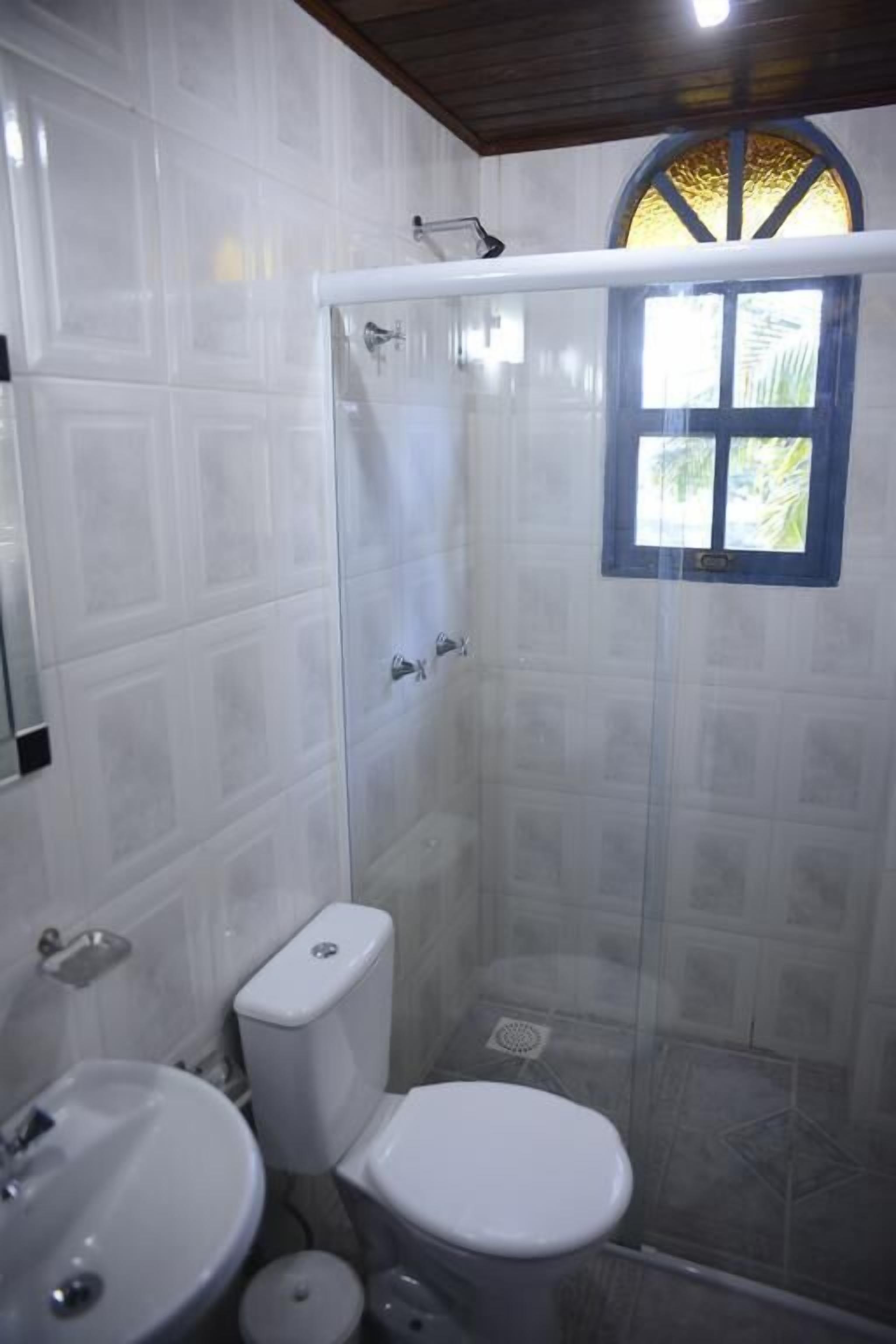 A bathroom with a glass-enclosed shower, a toilet, and a sink.
