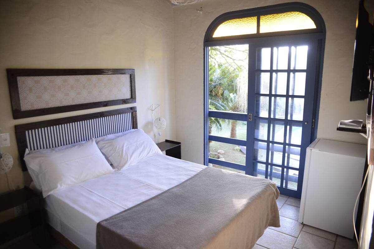 A bedroom with a bed, a nightstand, a dresser, and a door leading to a balcony.