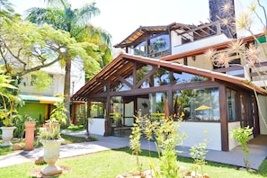 A modern house with a large glass window, a wooden deck, and a well-maintained garden.