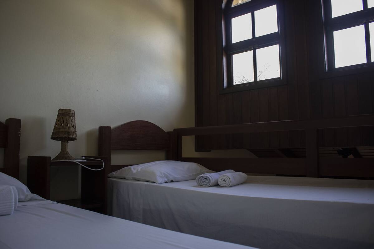 A room with a bed, a nightstand, a lamp, and a window.