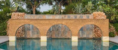 Una piscina al aire libre, sombrillas, sillones reclinables de piscina