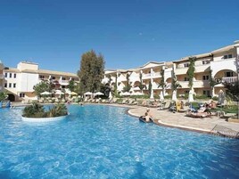 Un resort con piscina central, varios balcones y zonas de estar al aire libre.