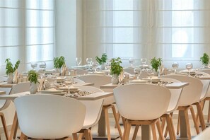A modern dining area with white chairs and tables, each set with wine glasses and small potted plants. - Bitzaro Grande Hotel - All Inclusive (Zakynthos)