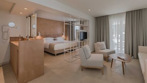 Moderni hotellihuone, jossa on sänky, televisio, työpöytä ja oleskelualue.