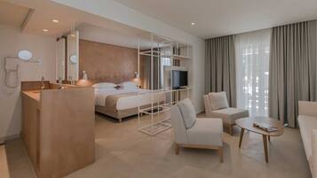 Een moderne hotelkamer met een bed, een televisie, een bureau en een zithoek.