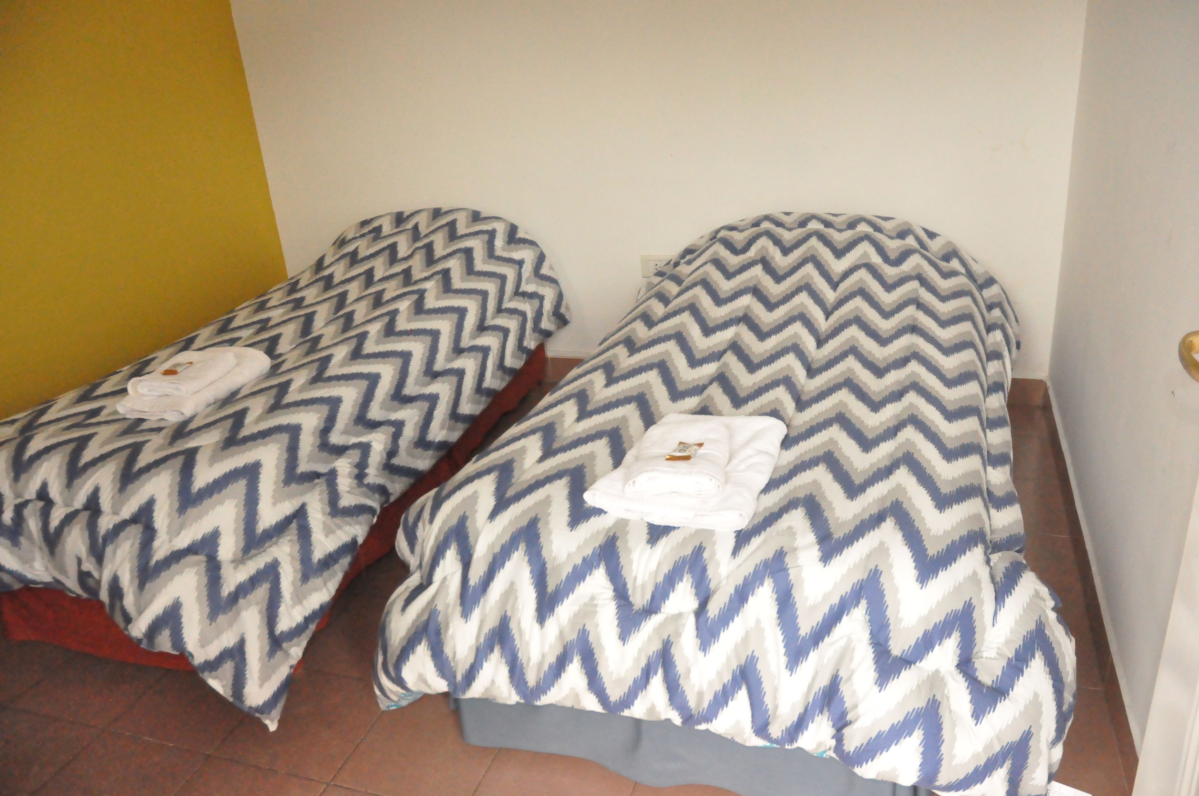 Dos camas individuales con ropa de cama y toallas estampadas.
