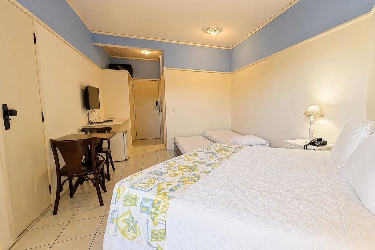 Une chambre d’hôtel comprenant un lit, un bureau avec une chaise, une table de chevet avec une lampe et un tableau au mur.