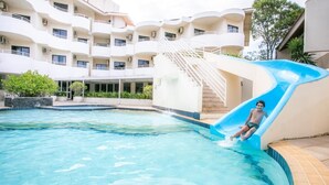A swimming pool with a blue slide, surrounded by a multi-story building with balconies. - Hotel Praia Brava (Florianópolis)