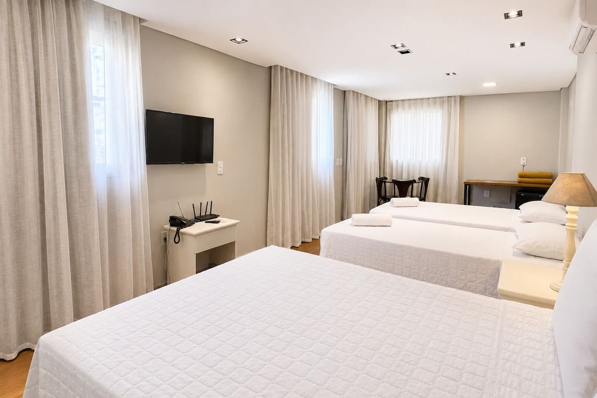 Une chambre d’hôtel avec deux lits, une télévision, un bureau avec un téléphone et une lampe.