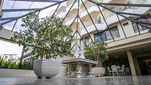 A modern atrium with a geometric glass ceiling, potted plants, and a fountain. - Hotel Praia Brava (Florianópolis)