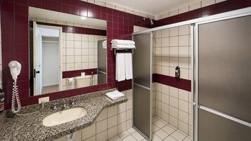 A bathroom with a sink, mirror, towel rack, and a shower area.