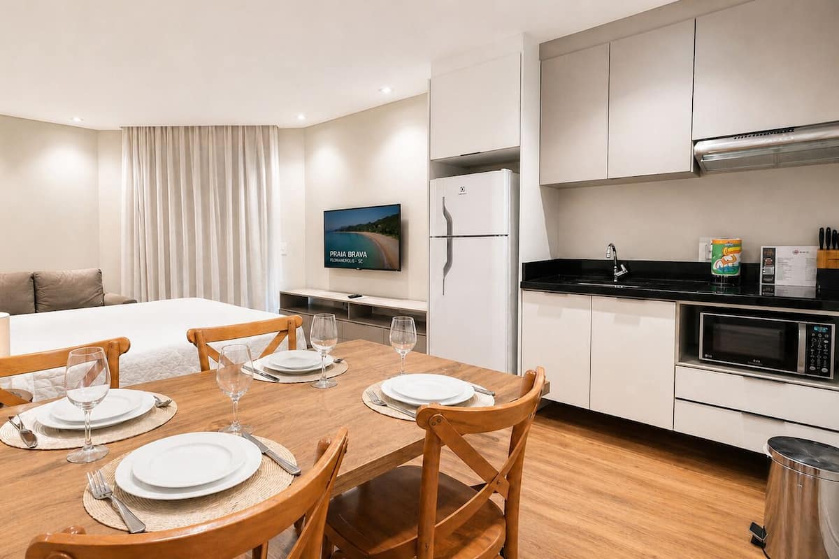 Une chambre d’hôtel équipée d’une table à manger pour quatre personnes, d’un lit avec vue, d’une kitchenette et d’un téléviseur à écran plat.