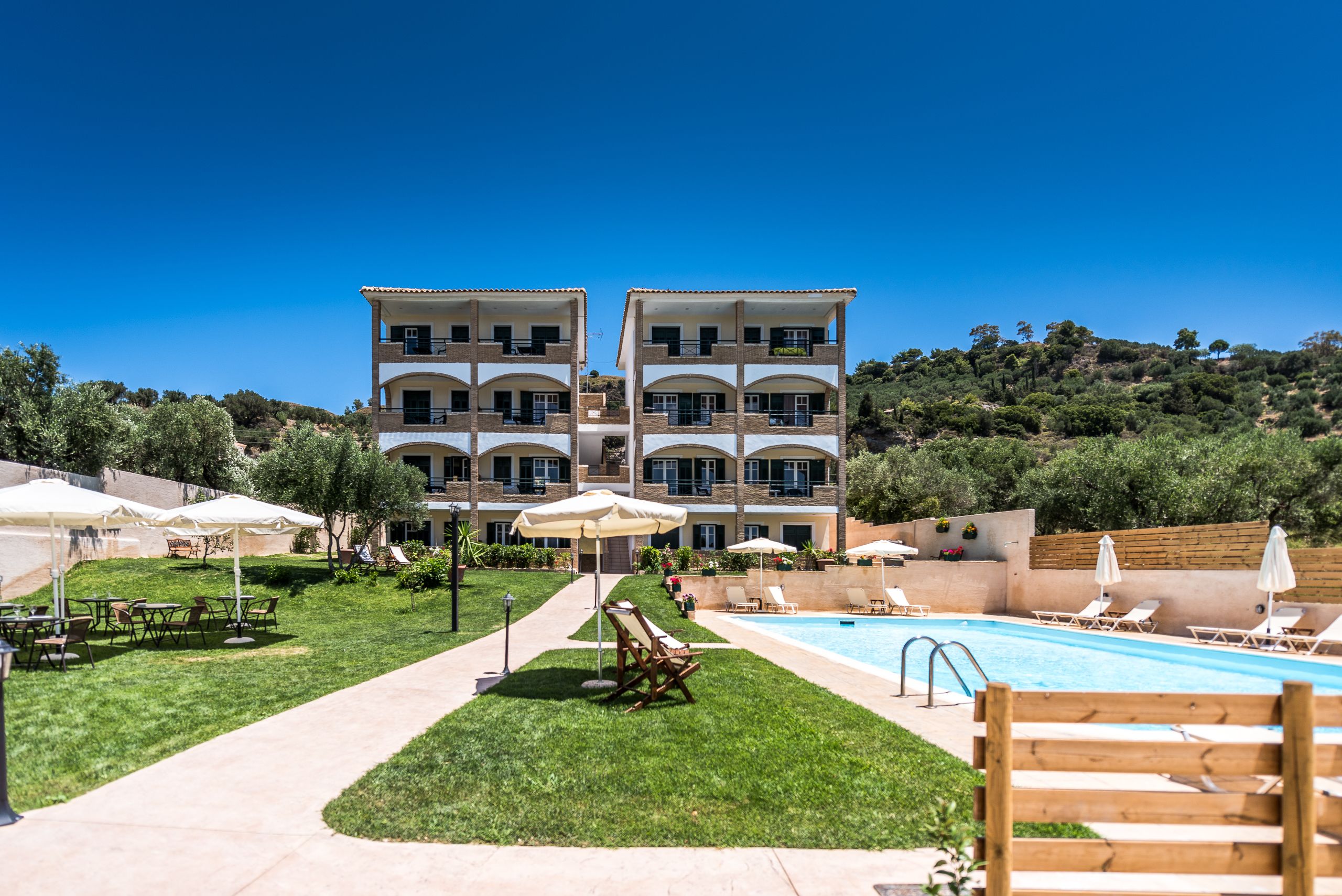 A hotel with a pool, outdoor seating, and a view of the surrounding landscape.