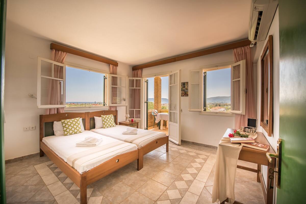 Habitación de hotel con dos camas, un escritorio y vistas al paisaje.