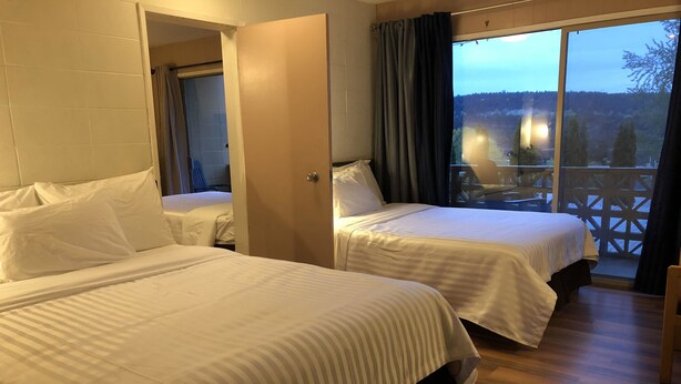 A hotel room with two beds, a balcony with a view of the forest, and a wooden floor. - Holiday House Motel (Ladysmith)