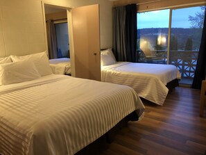 A hotel room with two beds, a balcony with a view of the forest, and a wooden floor. - Holiday House Motel (Ladysmith)