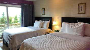 Hotellihuone, jossa on kaksi sänkyä, parveke, yöpöytä lampun kanssa ja seinällä oleva kehystetty kuva.