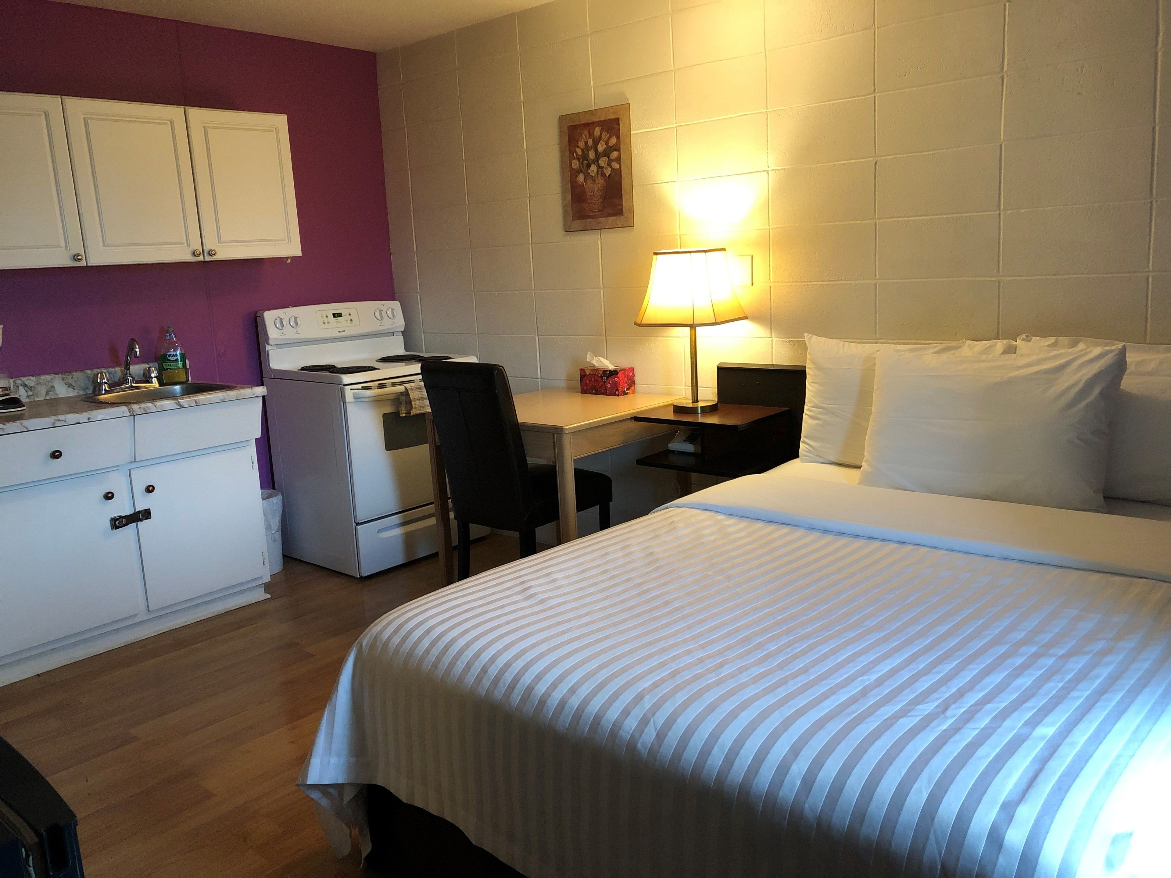Une chambre d’hôtel équipée d’un lit, d’un bureau, d’une chaise, d’une cuisinière et d’un évier.