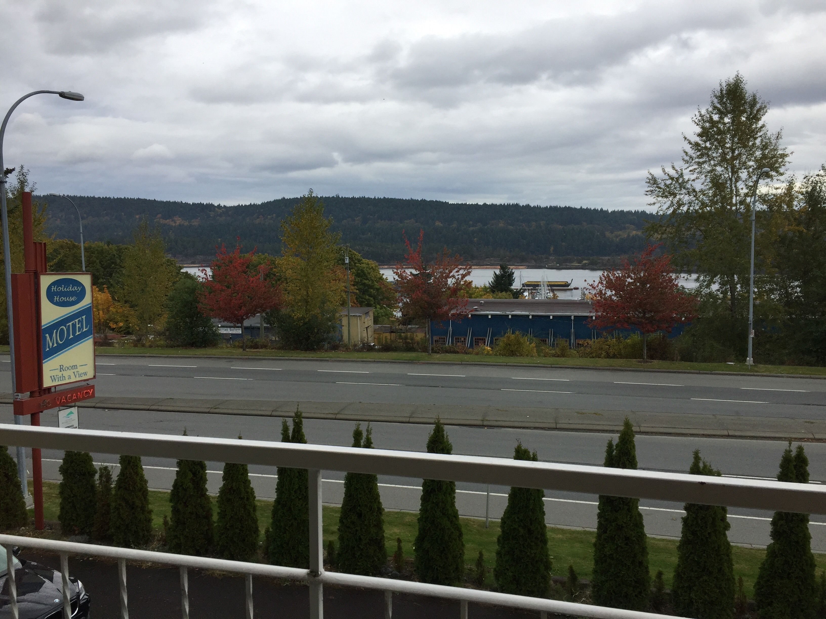 A motel sign with a view, a road, and a forested hill in the background.