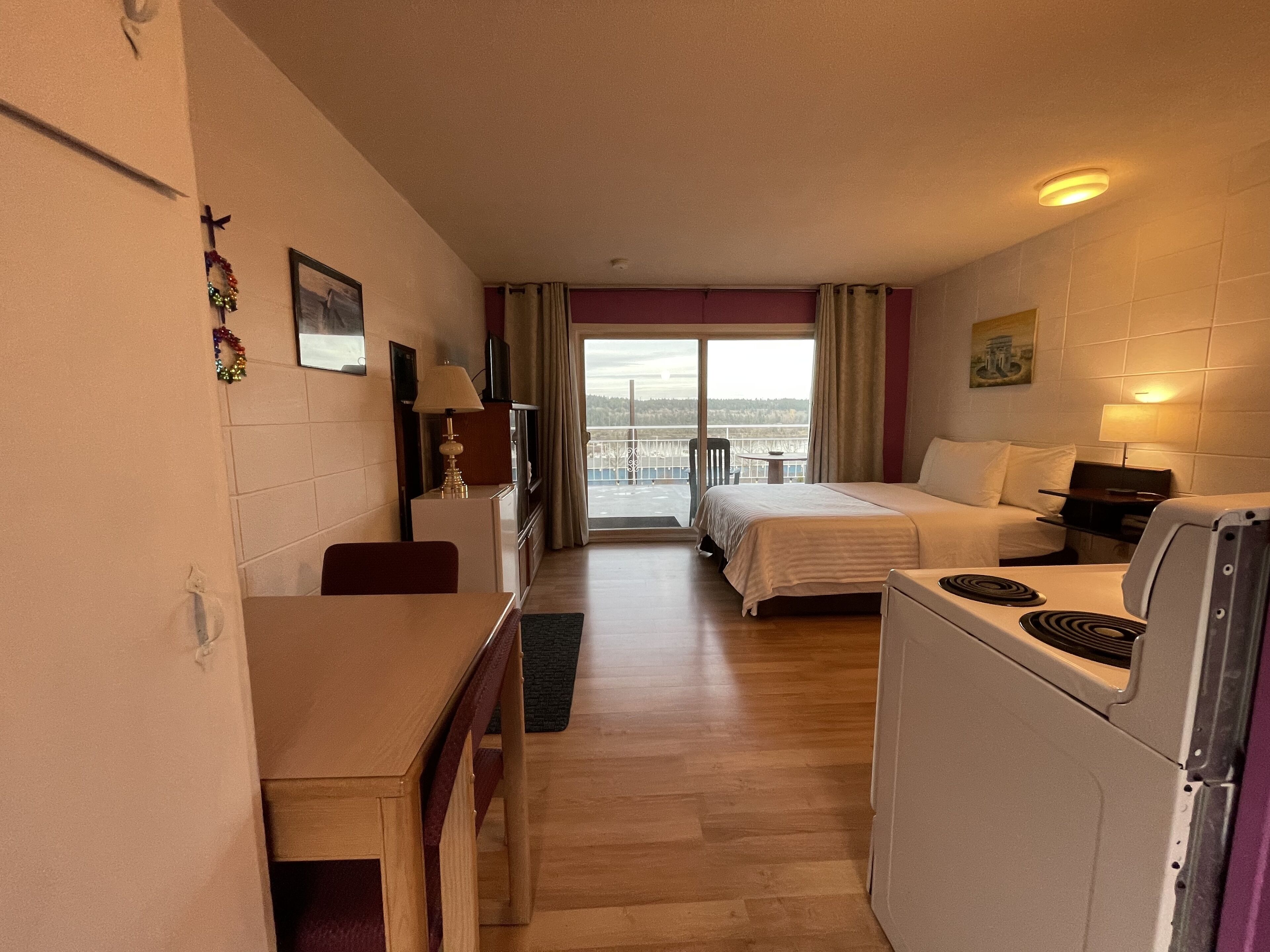 Habitación de hotel con cama, escritorio, silla, refrigerador y vista al exterior.