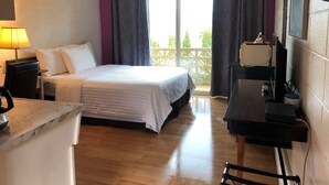 A hotel room with a bed, a desk with a computer, a lamp, and a view of the outside. - Holiday House Motel (Ladysmith)