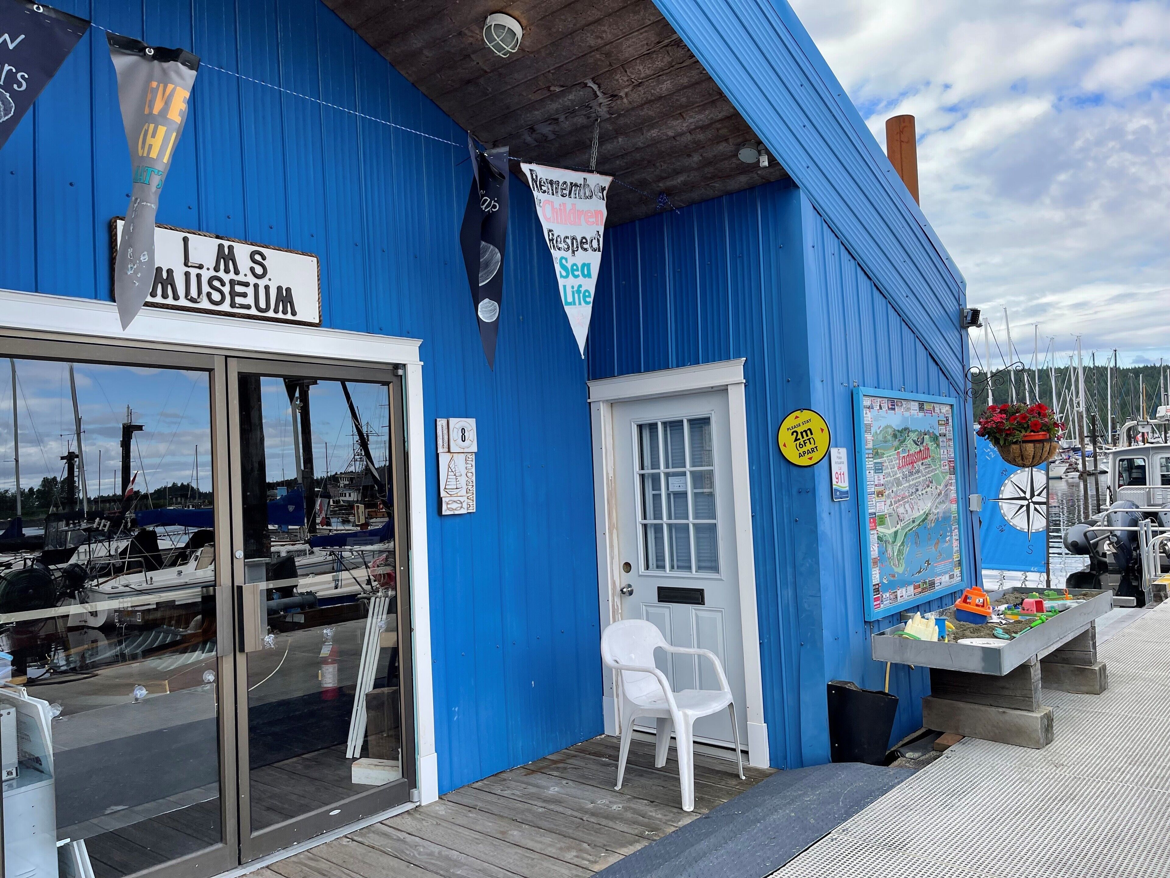 A blue building with a sign reading "L.M.S. Museum" and a white chair outside.