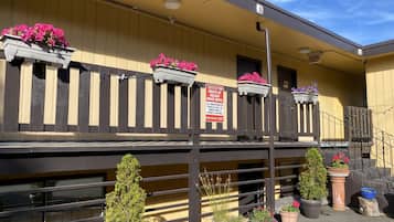 A motel with a balcony, potted plants, and a sign indicating guests of the motel.