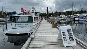 A marina with boats docked, a wooden pier, and a signboard. - Holiday House Motel (Ladysmith)