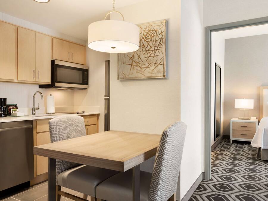 A hotel room with a dining area, kitchenette, and a bed.