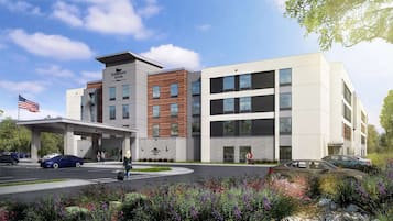 Et moderne hotel med et overdækket indgangsparti, flere etager og en anlagt have.
