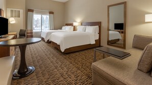 A hotel room with two beds, a desk, a chair, a sofa, and a large mirror. - Candlewood Suites Fargo South- Medical Center by IHG (Fargo)