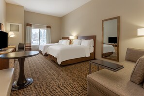 Une chambre d’hôtel avec deux lits, un bureau, une chaise, un canapé et un grand miroir.