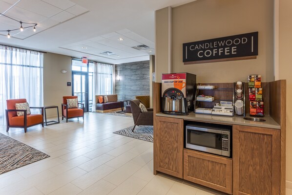 Un hall d’entrée moderne avec un espace café, un coin salon et un panneau indiquant la sortie.