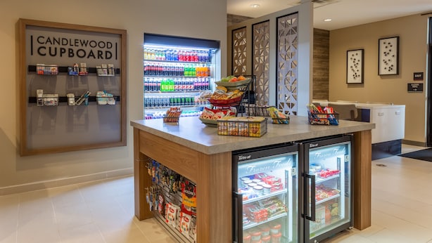 A hotel lobby with a Candlewood Cupboard, a refrigerated food display, and a snack bar. - Candlewood Suites Fargo South- Medical Center by IHG (Fargo)