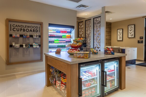 A hotel lobby with a Candlewood Cupboard, a refrigerated food display, and a snack bar.