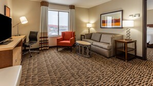 A hotel room with a desk, a chair, a sofa, a small round table, and a TV. - Candlewood Suites Fargo South- Medical Center by IHG (Fargo)