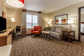 Une chambre d’hôtel équipée d’un bureau, d’une chaise, d’un canapé, d’une petite table ronde et d’un téléviseur.