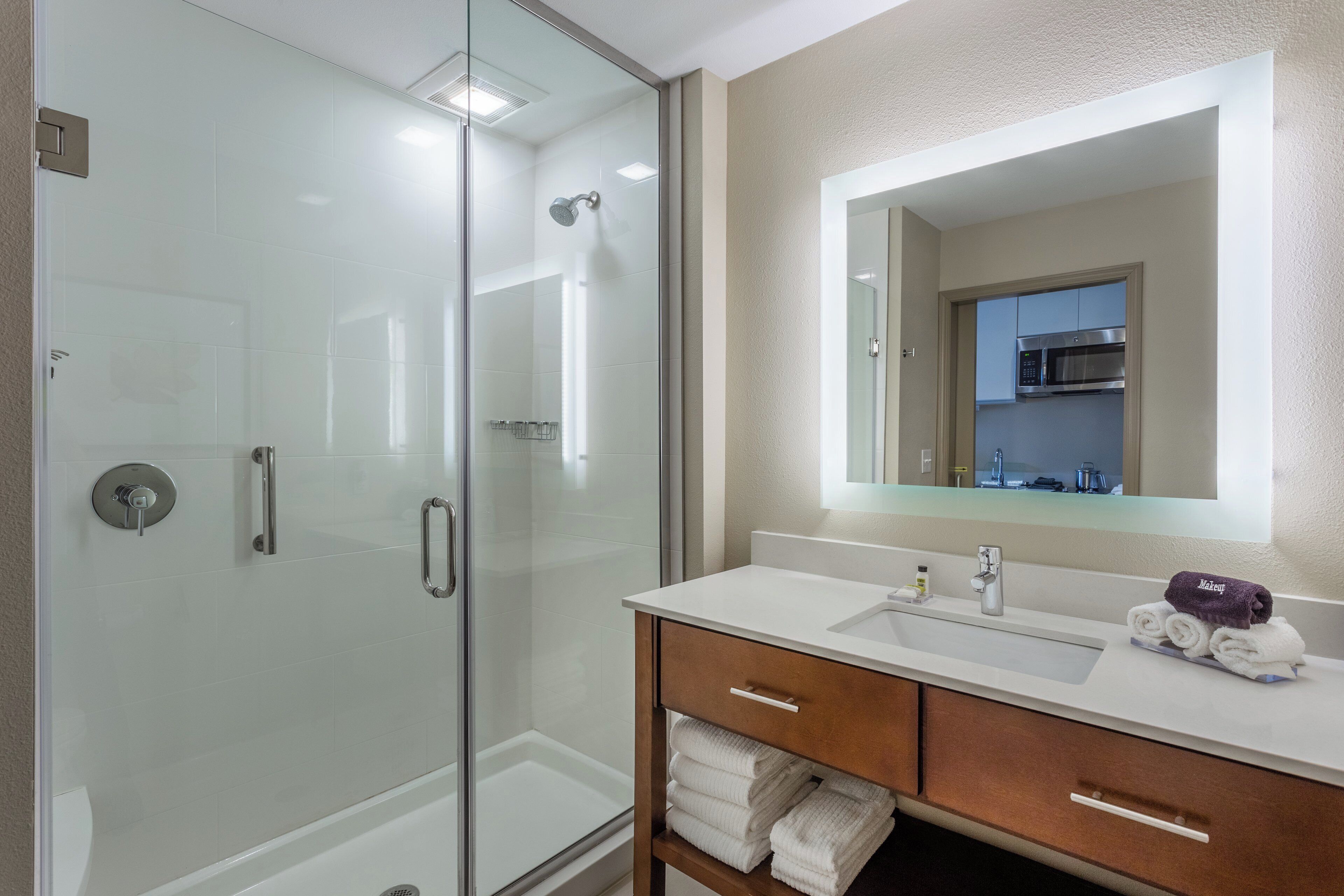 Een moderne badkamer met een douche met glazen wand, een wastafelmeubel met een wastafel en een spiegel erboven.