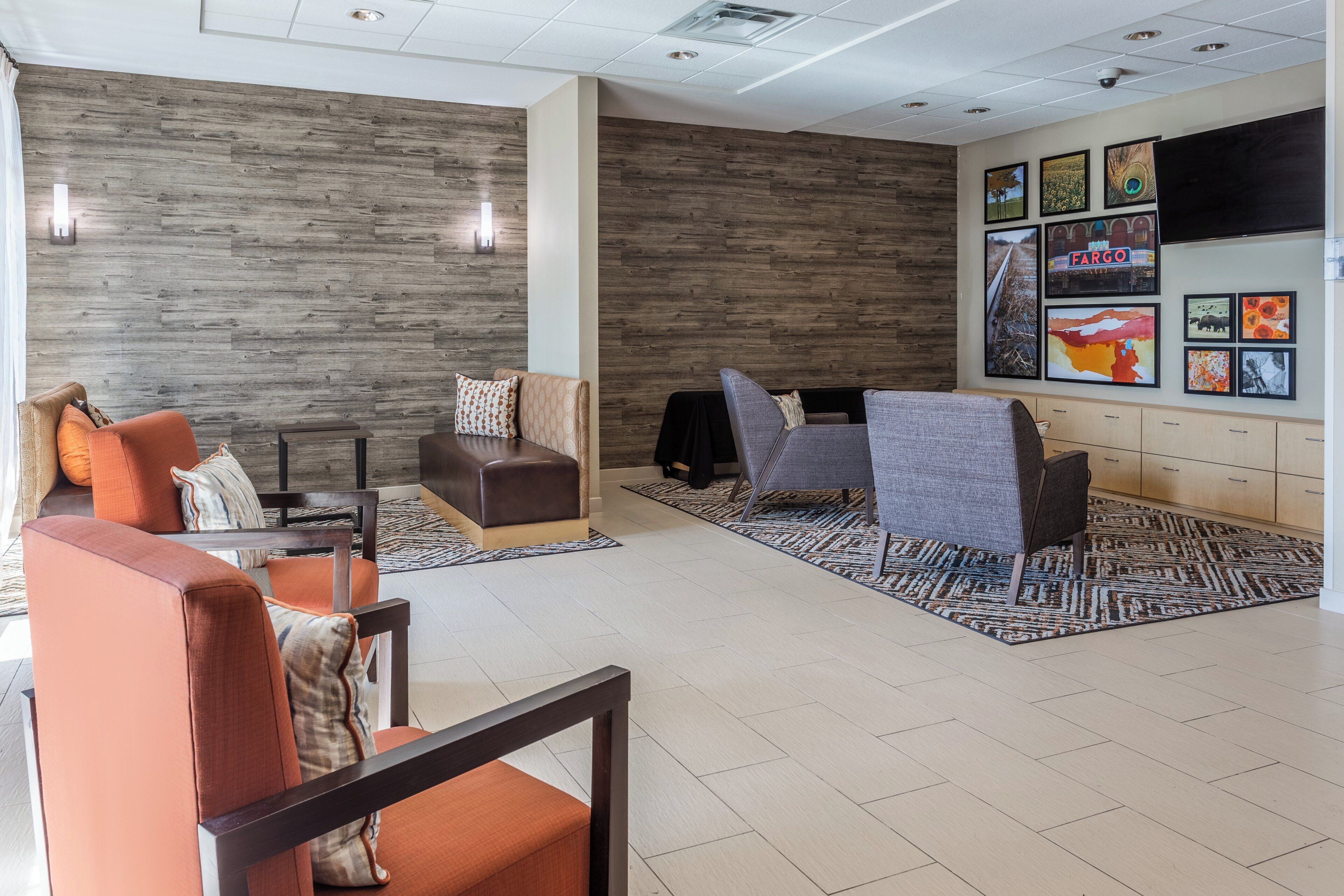 A modern lobby with seating arrangements, a wall-mounted TV, and artwork.