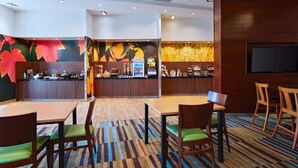 Un restaurante con mostrador, zona de mesas y una pantalla de televisión.