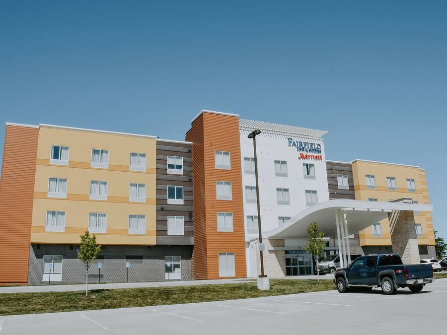 Hotel de vários andares com design moderno, destacando uma entrada imponente e uma área de estacionamento.